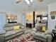 Open-concept living room with comfortable seating, neutral decor, and a view to the kitchen at 102 Dogwood Trl, Leesburg, FL 34748