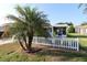 Front exterior with a mature palm tree and a white picket fence at 1070 Pinewood Pl, The Villages, FL 32162