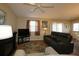 Cozy living room with a ceiling fan, sliding glass doors, and comfortable, dark sofa at 1070 Pinewood Pl, The Villages, FL 32162