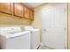 Laundry room features a side-by-side washer and dryer with upper cabinets and a white door at 1182 Allaire Loop, The Villages, FL 32163