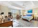Bright and airy main bedroom featuring a tray ceiling, plantation shutters, and a comfortable sitting area at 1182 Allaire Loop, The Villages, FL 32163
