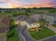 Sunset aerial showcasing a meticulously landscaped property on a golf course with a serene pond at 11820 Se 178Th St, Summerfield, FL 34491