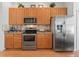 Well-lit kitchen with stainless steel appliances, wooden cabinets, and tiled backsplash at 11820 Se 178Th St, Summerfield, FL 34491