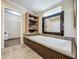Elegant bathroom featuring a soaking tub with dark wood trim, a mirror, and walk-in closet at 1236 Elkhart Cir, Tavares, FL 32778