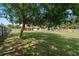 Expansive backyard featuring a large shade tree, lush lawn, and a view of the home's patio area at 13336 Biscayne Dr, Grand Island, FL 32735