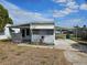 Modest single-story home with covered parking and small porch under a blue sky at 1425 County Dr, Tavares, FL 32778