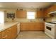 Well-lit kitchen featuring white appliances, lots of wood cabinets, and new floors at 1482 Azteca Loop, The Villages, FL 32162