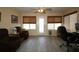 Cozy living room with gray hardwood floors, ceiling fan, woven shades, comfortable recliner chairs and views of the backyard at 1482 Azteca Loop, The Villages, FL 32162