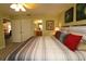 Comfortable main bedroom featuring a ceiling fan, ensuite bath, and a king bed with wood frame and soft, neutral-toned bedding at 1482 Azteca Loop, The Villages, FL 32162