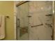 Luxurious shower with marble-style walls, a built-in seat, a hand-held shower wand and grab bars for safety and comfort at 1482 Azteca Loop, The Villages, FL 32162