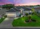 Beautiful single-story home with well-manicured lawn, mature landscaping, and two-car garage under a purple sunset sky at 17471 Se 110Th Ter, Summerfield, FL 34491