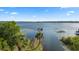 A serene aerial view of a lake with a dock, surrounded by lush trees and a clear blue sky at 19627 Spring Oak Dr, Eustis, FL 32736