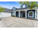 Front view of blue home featuring a brick facade, white trim, and a spacious driveway at 19627 Spring Oak Dr, Eustis, FL 32736