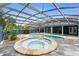 Expansive screened-in pool area with a spa, pool, and lush tropical landscaping at 19627 Spring Oak Dr, Eustis, FL 32736