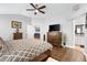 Inviting main bedroom featuring wood floors, fan, dresser, TV and ensuite bathroom entrance at 2015 Palo Alto Ave, The Villages, FL 32159