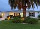 Charming single-story home featuring a manicured lawn and mature landscaping at twilight at 2022 Claudio Ln, The Villages, FL 32159