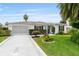 Charming single-story home featuring a manicured lawn, mature landscaping, and a concrete driveway with a unique design at 2022 Claudio Ln, The Villages, FL 32159