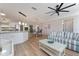 Bright living room with wood floors, white kitchen and stylish striped couch under a ceiling fan at 2022 Claudio Ln, The Villages, FL 32159