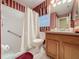 Cozy bathroom with striped wallpaper, a shower with curtain, and a wood-paneled vanity sink at 2131 Burley Ave, Clermont, FL 34711