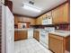 Cozy kitchen featuring wood cabinets, white appliances, and unique wallpaper at 2131 Burley Ave, Clermont, FL 34711