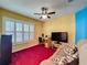 Cozy living room with red carpet, neutral colored sofa, and a ceiling fan at 2131 Burley Ave, Clermont, FL 34711