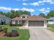 Charming single-story home featuring a well-manicured lawn, beautiful landscaping, and a two-car garage at 22217 Caledonia Dr, Leesburg, FL 34748