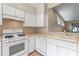 Well-lit kitchen featuring white cabinets, tile floors, neutral countertops, and a functional layout at 22217 Caledonia Dr, Leesburg, FL 34748