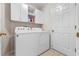 Bright laundry room with a Whirlpool washer and dryer, white cabinets, and a tiled floor at 22217 Caledonia Dr, Leesburg, FL 34748