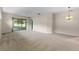 Bright living room featuring neutral walls, carpeting, sliding glass doors, and a ceiling fan at 22217 Caledonia Dr, Leesburg, FL 34748