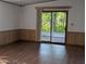 A living room featuring a sliding glass door to the patio with paneled walls at 2871 Myakka River Rd, Tavares, FL 32778