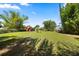 Large, green backyard with mature trees and landscaping, plus a charming red barn at the edge of the property at 28924 Discovery Rd, Tavares, FL 32778