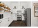 Modern kitchen with stainless appliances, white cabinetry, subway tile backsplash, floating shelves and dark stone flooring at 28924 Discovery Rd, Tavares, FL 32778