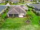 Beautiful backyard with lush green grass, landscaping, mature trees, and a screened in lanai at 2954 Cedar Grove Loop, The Villages, FL 32163