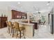 Spacious kitchen with dark wood cabinets, granite counters, tile backsplash, an island, and barstool seating at 2954 Cedar Grove Loop, The Villages, FL 32163