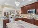 A kitchen with dark wood cabinets and granite countertops open to the dining area at 2954 Cedar Grove Loop, The Villages, FL 32163