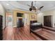 Well-lit main bedroom showcasing hardwood floors, modern ceiling fan, and direct access to the en-suite at 2954 Cedar Grove Loop, The Villages, FL 32163