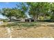 Grassy backyard featuring mature trees, garage, and screened pool at 307 Water Shore Dr, Leesburg, FL 34748