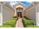 Elegant entryway featuring a decorative glass door, complemented by lush landscaping and a brick pathway at 3319 Barrington Ct, The Villages, FL 32162