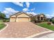 Charming single-story home boasts a two-car garage and a brick-paved driveway, complemented by lush landscaping at 3319 Barrington Ct, The Villages, FL 32162