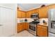 A modern kitchen with stainless steel appliances, stone countertops, and warm wood cabinetry at 3319 Barrington Ct, The Villages, FL 32162
