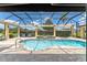 Screened-in pool area featuring a spa, waterfall feature, grill and outdoor seating under blue skies at 3319 Barrington Ct, The Villages, FL 32162
