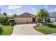 Inviting home exterior with a well-manicured lawn, palm trees, and a spacious driveway at 3433 Nestlebranch Ave, The Villages, FL 32163