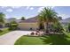 Charming single-story home featuring a well-manicured lawn, mature palm trees, and a welcoming two-car garage at 3433 Nestlebranch Ave, The Villages, FL 32163