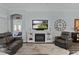 Open living room features a fireplace and TV, comfortable seating, a clock, and open doorway to other rooms at 3433 Nestlebranch Ave, The Villages, FL 32163