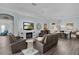 Open living room features hardwood floors, fireplace and TV, comfortable seating, a dining room and an open doorway at 3433 Nestlebranch Ave, The Villages, FL 32163