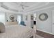 Bright main bedroom features a tray ceiling, hardwood floors, a ceiling fan, windows, and doorway to bathroom at 3433 Nestlebranch Ave, The Villages, FL 32163