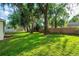 Large, well-kept backyard featuring a lush lawn, mature trees providing shade, and privacy fencing at 35107 Sweet Leaf Ln, Leesburg, FL 34788