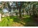 Spacious backyard with lush green grass, mature trees, and a well-maintained fence at 35107 Sweet Leaf Ln, Leesburg, FL 34788