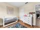 Bright Bedroom equipped with a crib, dresser, and wooden floors at 35107 Sweet Leaf Ln, Leesburg, FL 34788