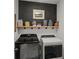 Functional laundry room with black and white appliances and a wooden shelf at 35107 Sweet Leaf Ln, Leesburg, FL 34788